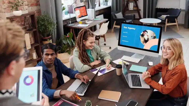 Equipo de una agencia reunido con laptops analiza el costo y el retorno de cada modelo para generar leads