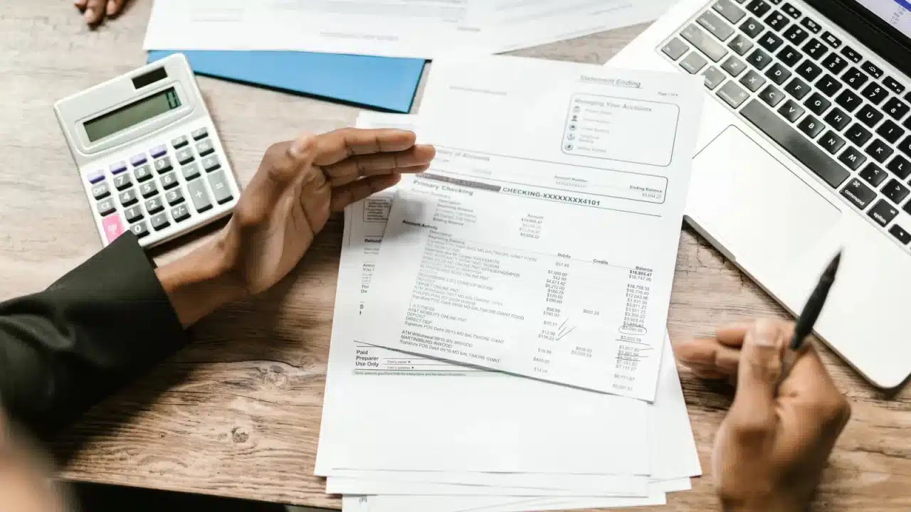Manos con calculadora y planillas impresas calculan el costo y el retorno de dejar de depender de referidos