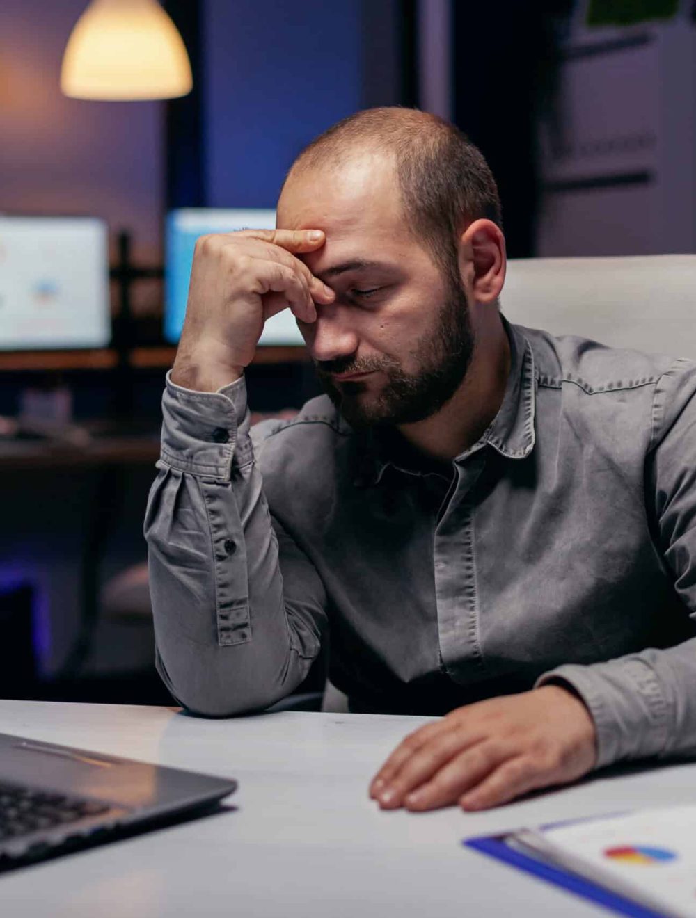 Overworked businessman sleeping resting his head on his hand. Workaholic employee falling asleep because of working late at night alone in the office for important company project.